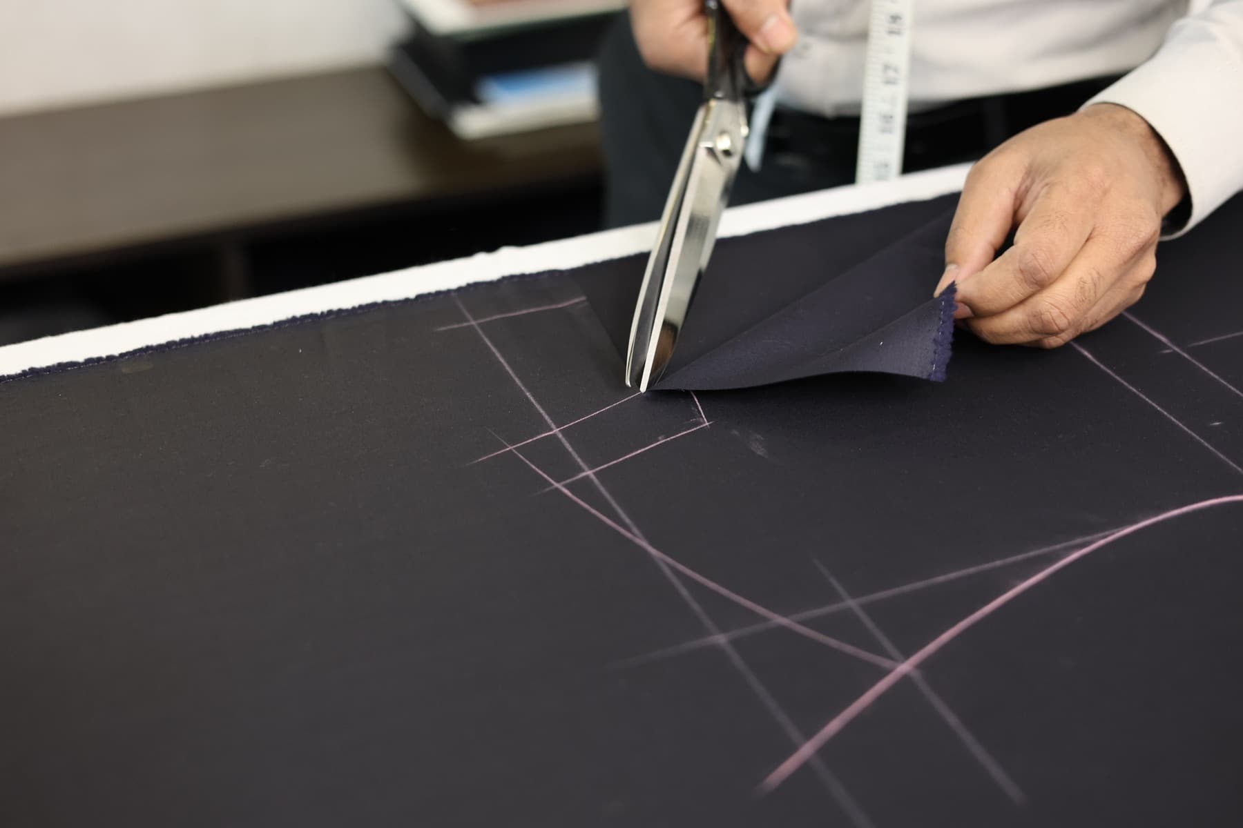 Master tailor making the first cut on dark cloth
